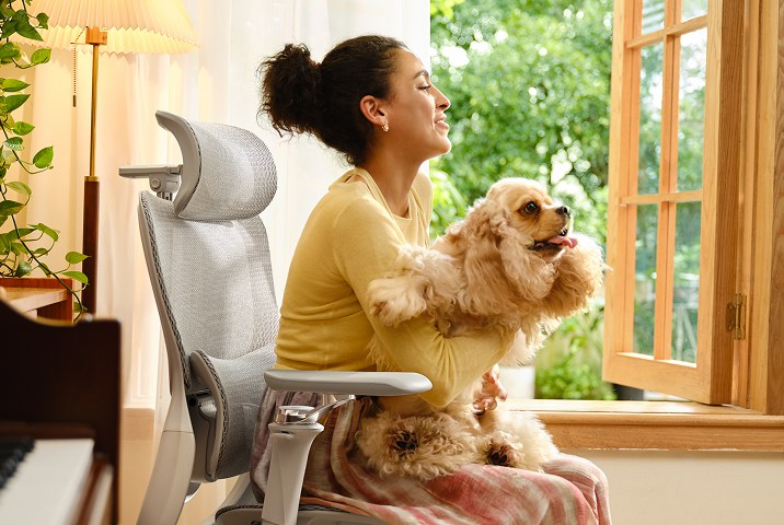 Woman holding a dog sitting in HBADA ergonomic chair relaxing