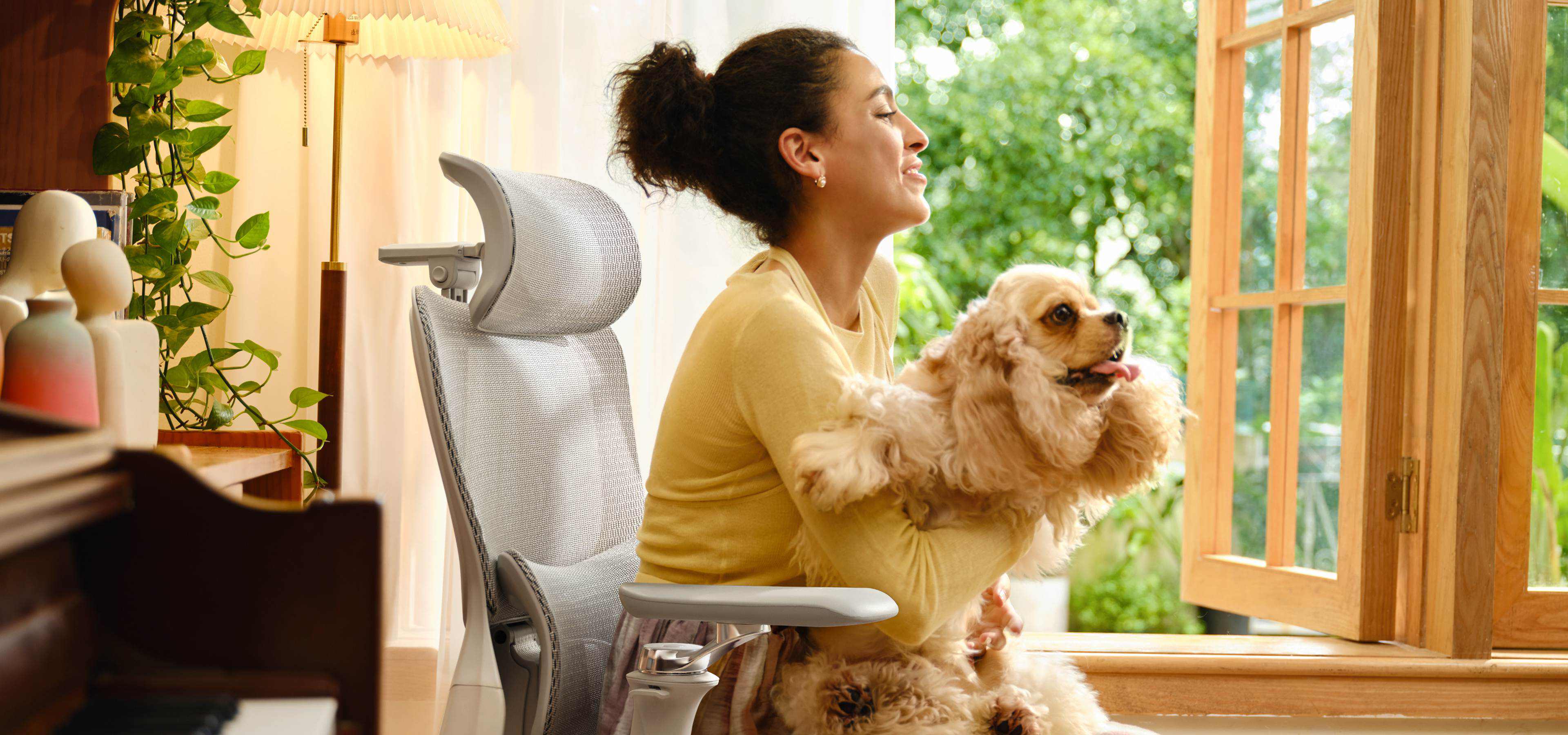 Woman holding a dog in a home setting sitting in HBADA ergonomic chair relaxing